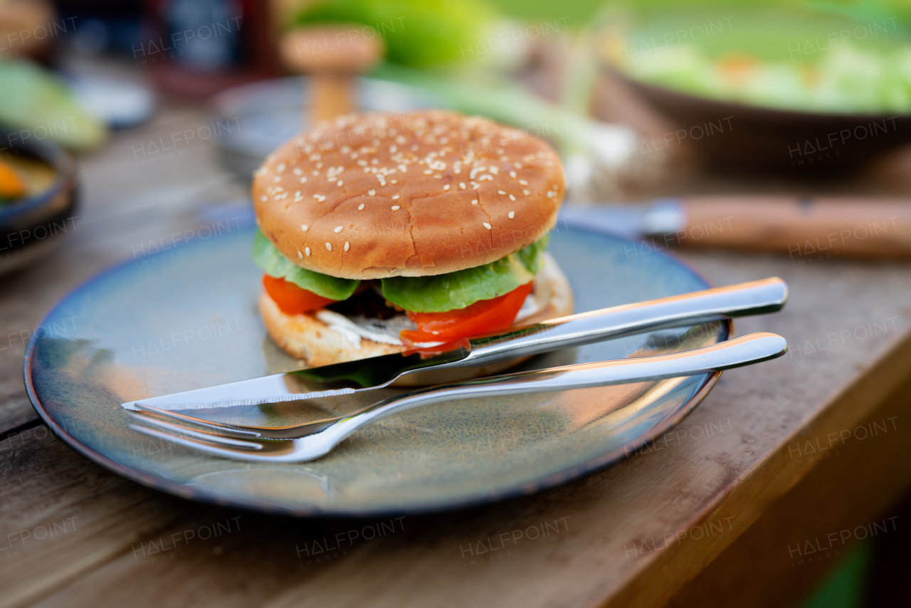 Close up of plate with homemade grilled hamburger and cutlery.