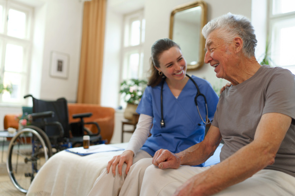 Young nurse taking care of elderly senior in his home.