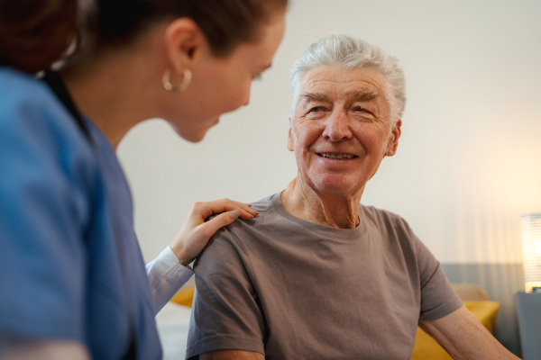 Young nurse taking care of elderly senior in his home.