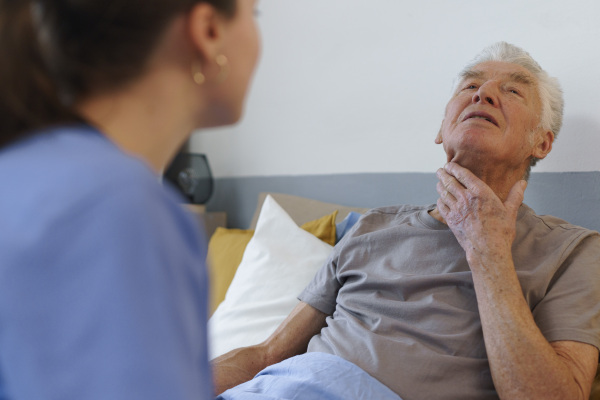 Young nurse taking care of elderly senior in his home.