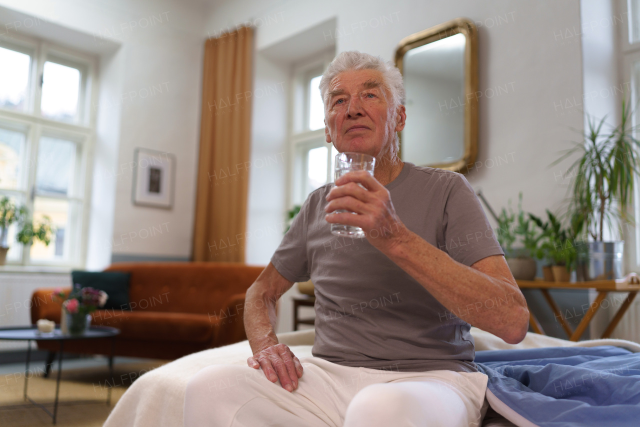 Portrait of senior man drinking water after taking a pills. Importance of hydration for the elderly.