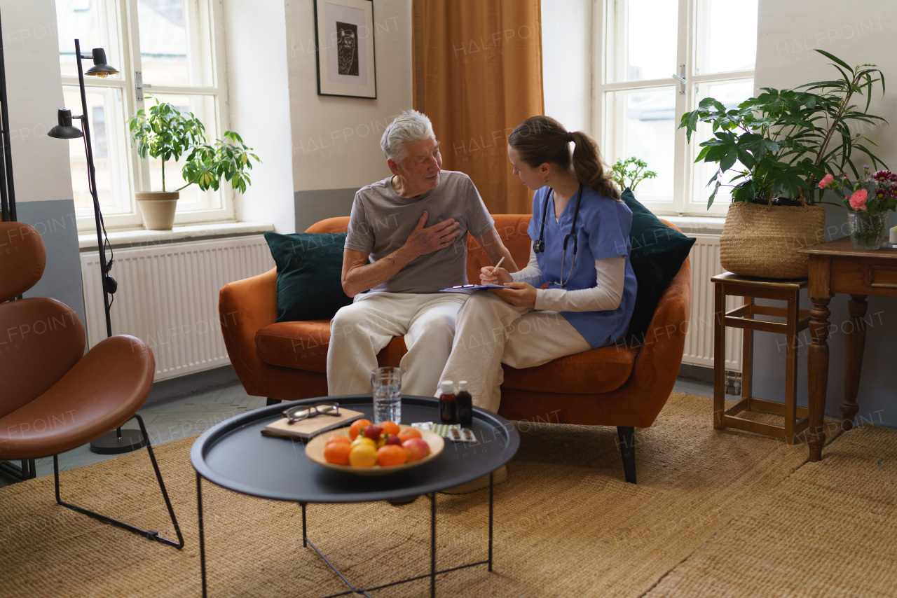 Young nurse taking care of elderly senior in his home.