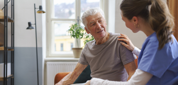 Young nurse taking care of elderly senior in his home.