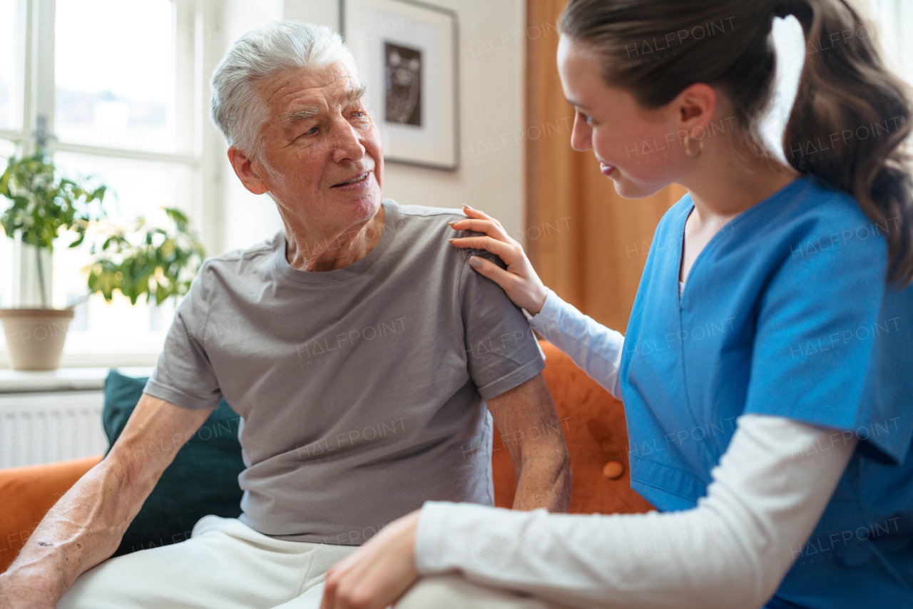 Young nurse taking care of elderly senior in his home.