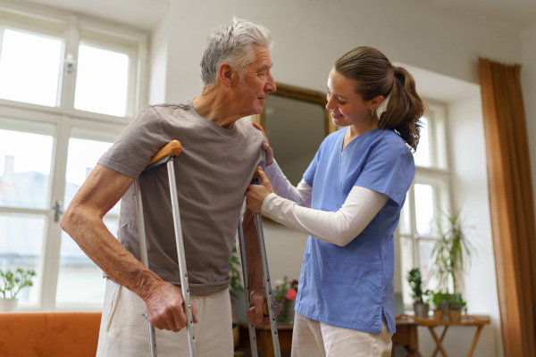 Young nurse helping a senior man with walking.