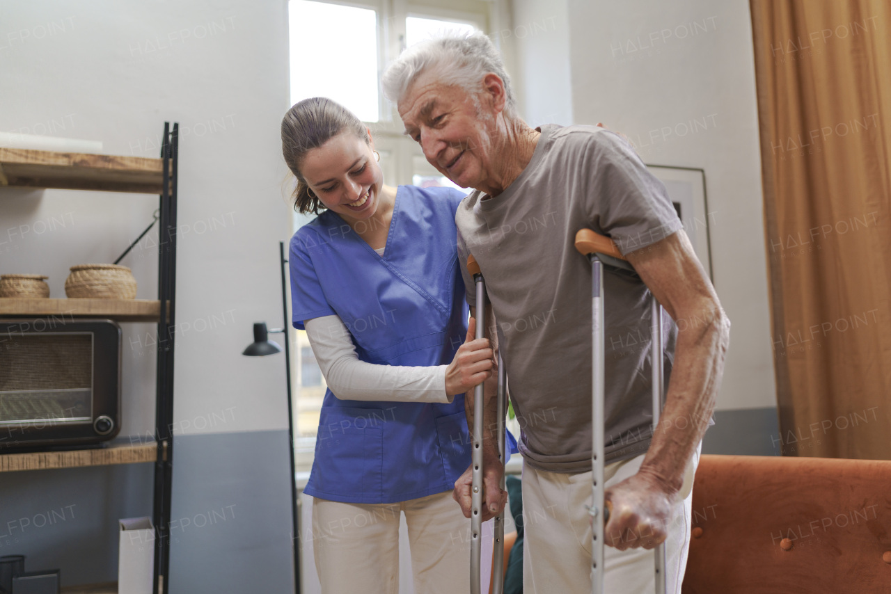 Young nurse helping a senior man with walking.