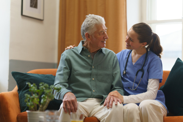 Young nurse taking care of elderly senior in his home.