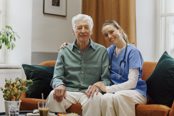 Young nurse taking care of elderly senior in his home.