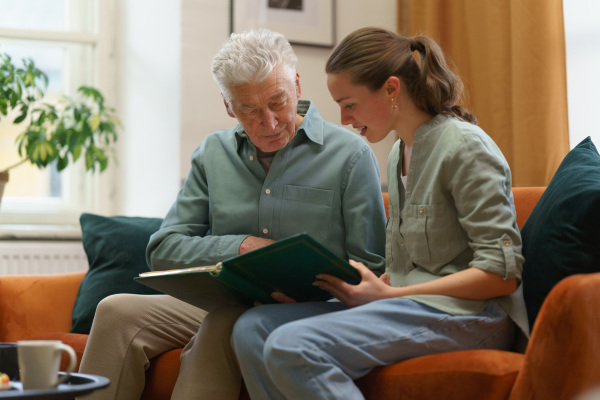 Senior man with his grandaughter reading book.