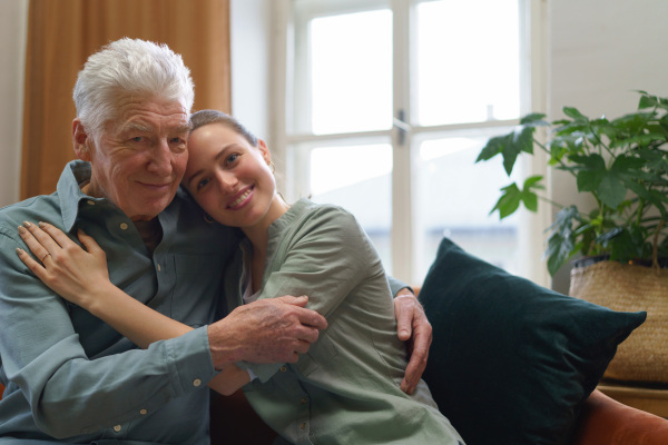 Young woman hugging her grandfather in the home.