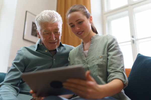 Senior man with his granddaughter using digital tablet together.