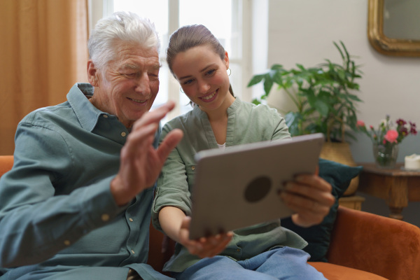 Senior man with his granddaughter using digital tablet together.