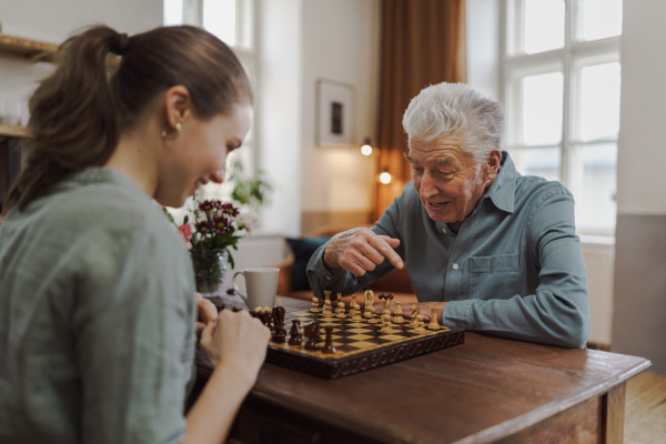 Senior man playing chess with his caregiver.