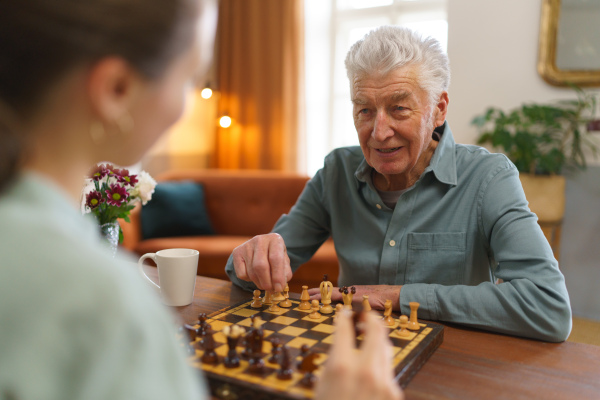 Senior man playing chess with his caregiver.