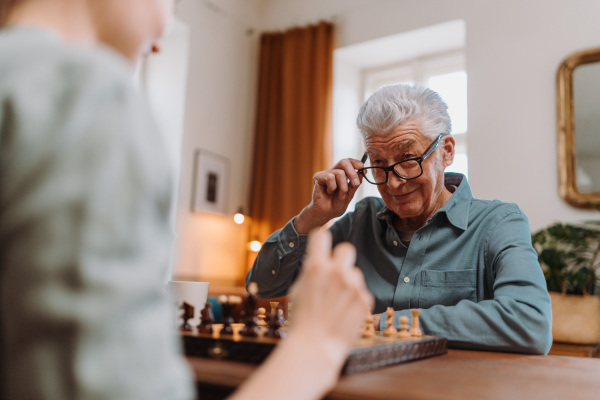 Senior man playing chess with his caregiver.