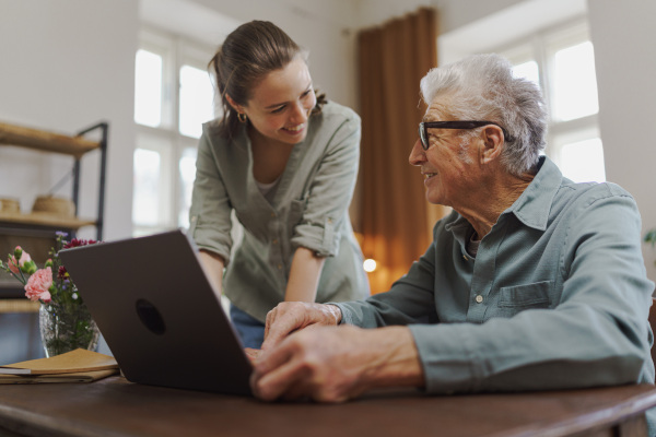 Granddaughter showing something to her grandfather on a laptop.