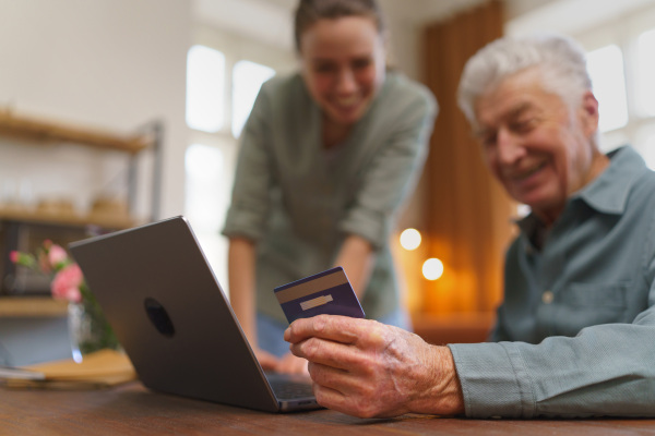 Senior man with his caregiver online shopping at notebook.