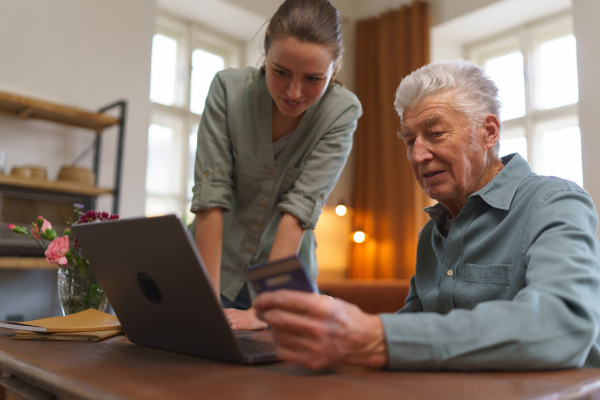 Senior man with his caregiver online shopping at notebook.