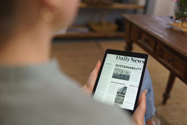 Detail of tablet with news article on screen. Woman reading news in digital tablet.