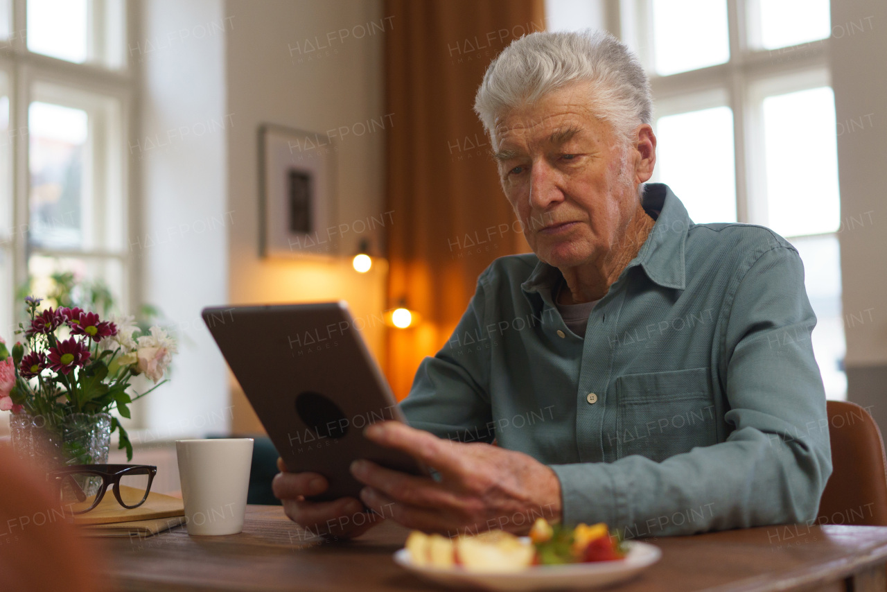 Senior man reading something in a digital tablet.