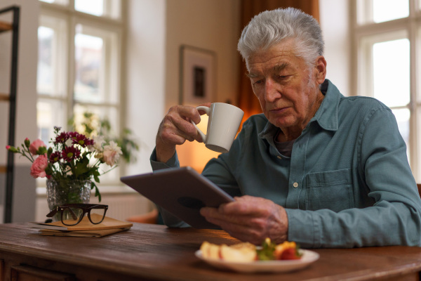 Senior man reading something in a digital tablet.