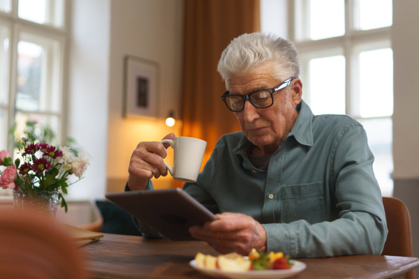 Senior man reading something in a digital tablet.