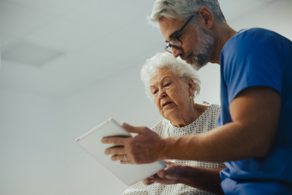 Supportive doctor soothing a worried senior patient, discussing test result in emergency room. Compassionate emotional support for elderly patient.