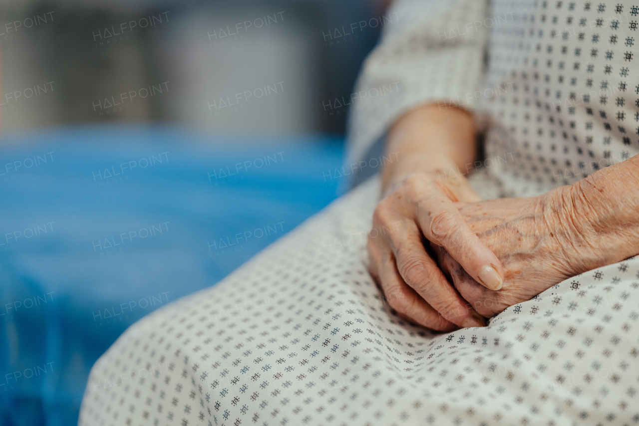 Close up of hands of a senior female patient on examination table in the hospital. Concept of fear and anxiety about health problems in elderly people.