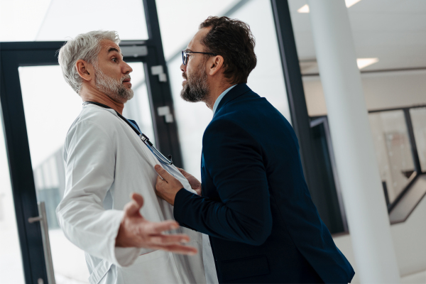 Violence against health workers. Patient is aggressive, have conflict with doctor in the hospital corridor. Visitor holding doctor by coat, screaming, threatening him.