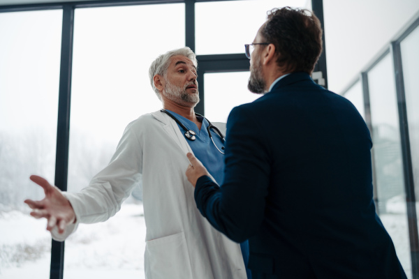 Violence against health workers. Patient is aggressive, have conflict with doctor in the hospital corridor. Visitor holding doctor by coat, screaming, threatening him.