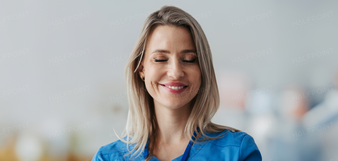 Banner of confident female doctor with closed eyes in hospital. Smiling beautiful nurse wearing blue uniform, holding clipboard standing in modern private clinic.