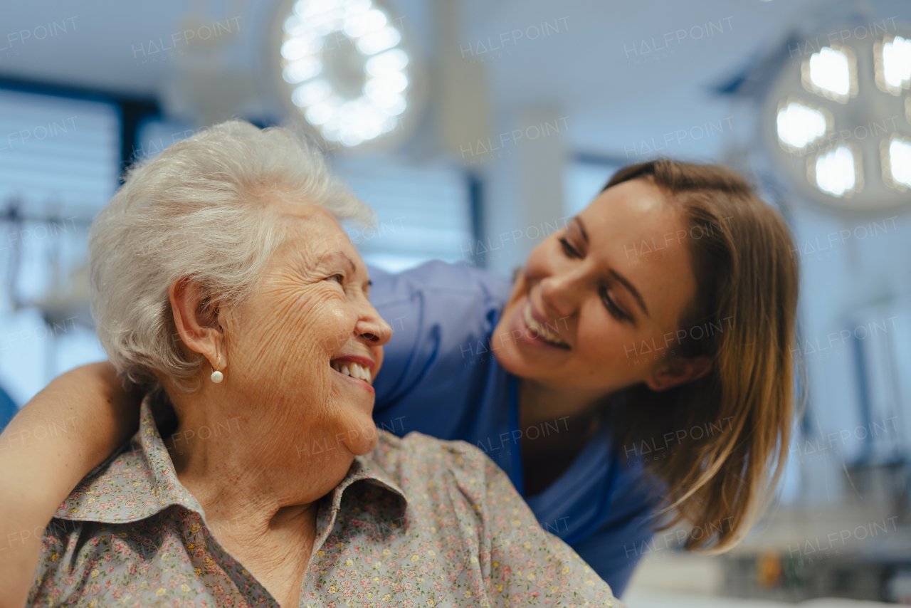 Portrait of caring nurse and senior patient talking in hospital corridor. Emotional support for elderly woman.