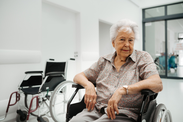 Portrait of senior patient in wheelchair. Elderly woman in the hospital waiting for medical examination, feeling anxious, scared and alone.