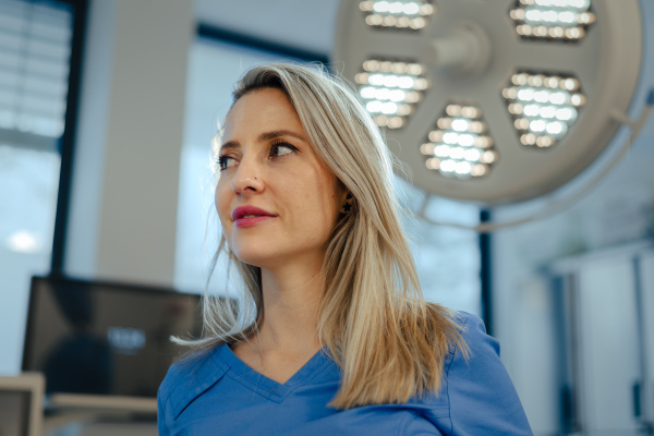 Portrait of ER doctor in hospital working in emergency room. Portrait of the beautiful nurse in blue uniform, low angle shot.