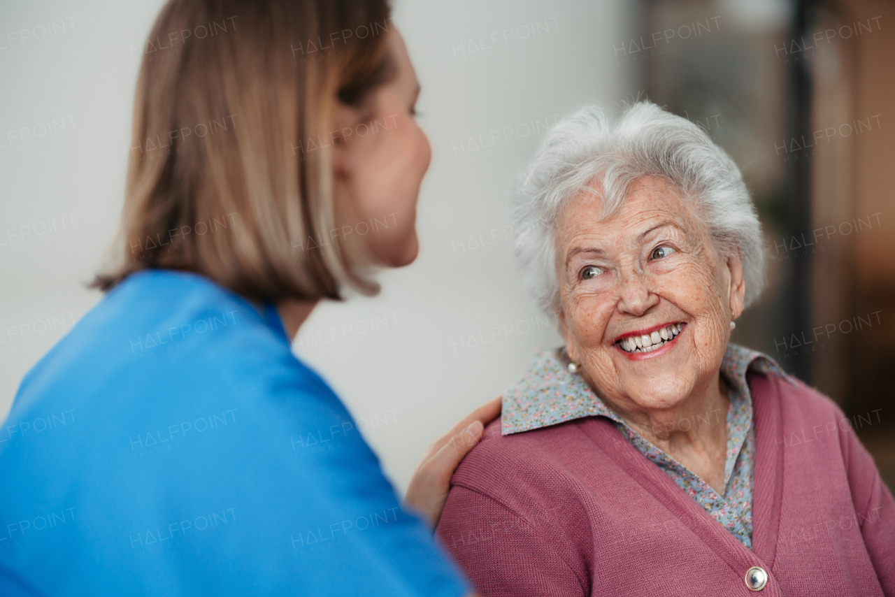 Portrait of caring nurse and senior patient talking in hospital corridor. Emotional support for elderly woman.