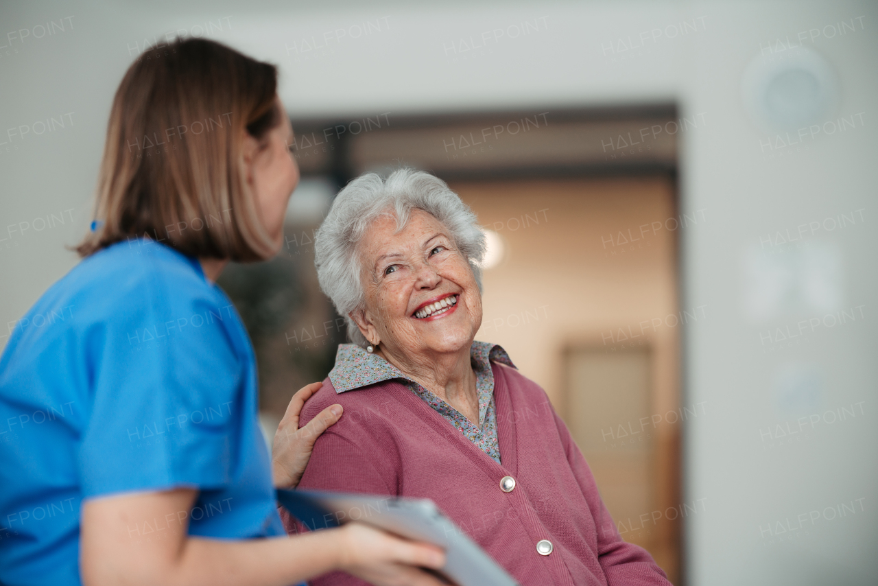 Portrait of caring nurse and senior patient talking in hospital corridor. Emotional support for elderly woman.