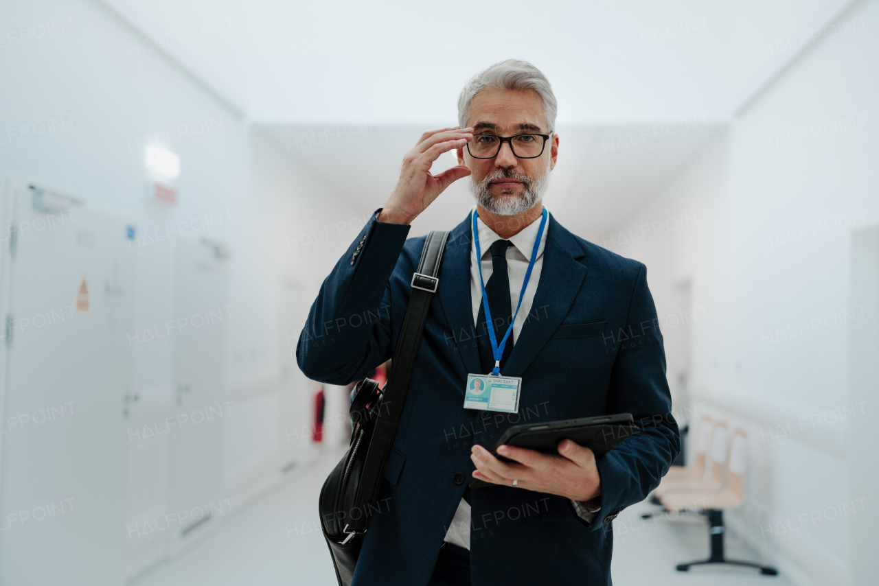 Portrait of pharmaceutical sales representative in medical building, waiting for doctor, presenting new pharmaceutical product. Smiling drug rep standing in hall, modern medical clinic, holding tablet.