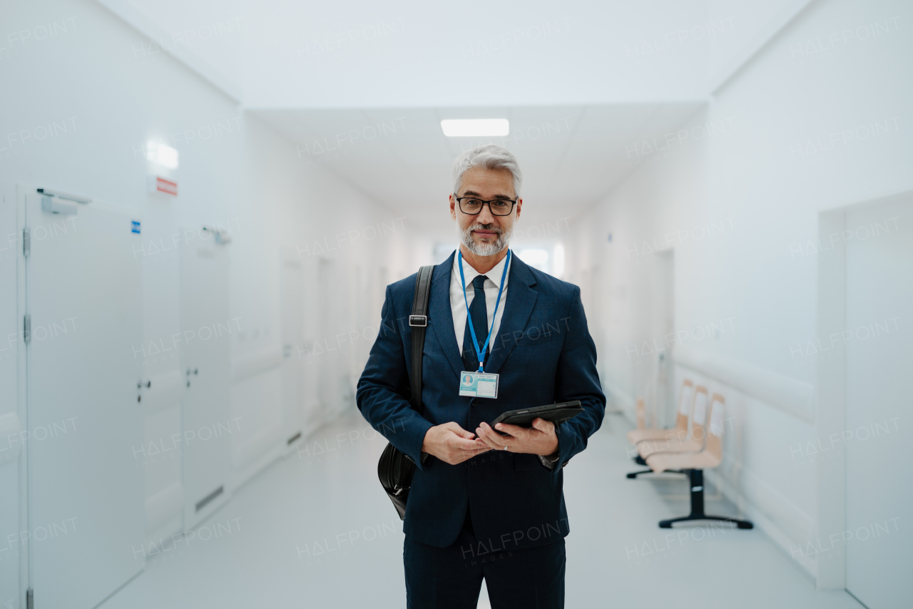 Portrait of pharmaceutical sales representative in medical building, waiting for doctor, presenting new pharmaceutical product. Smiling drug rep standing in hall, modern medical clinic, holding tablet.