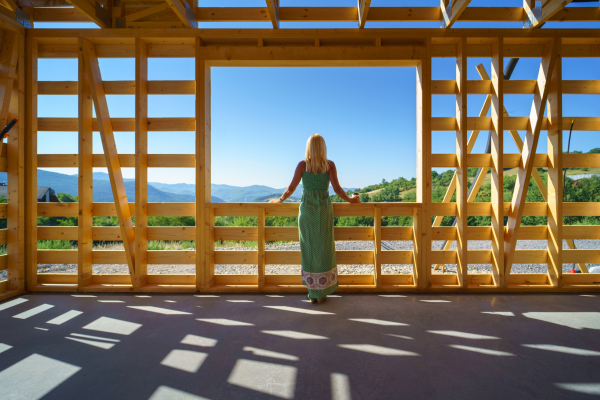 Senior woman on site inside construction framing dreaming of her home and looking at view.