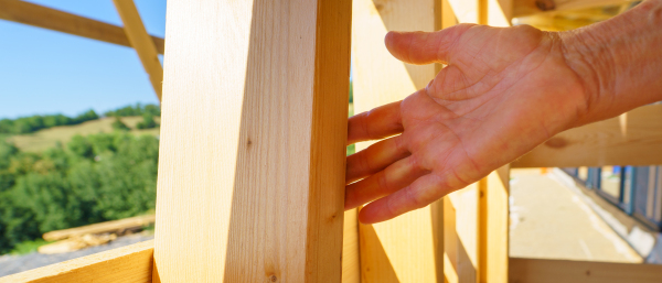 Close-up of a woman hand touching wooden eco house framing. Concept of sustainability and healthy living.