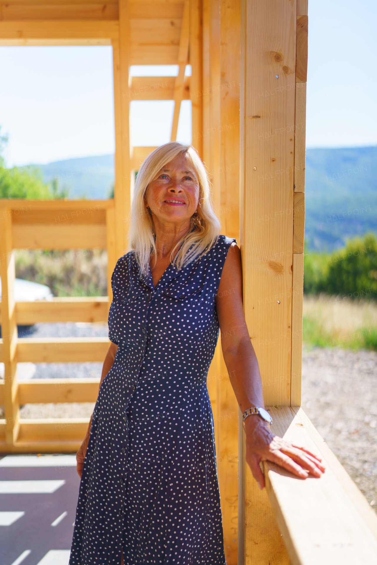 A happy senior woman inside of her new unfinished ecological wooden house.