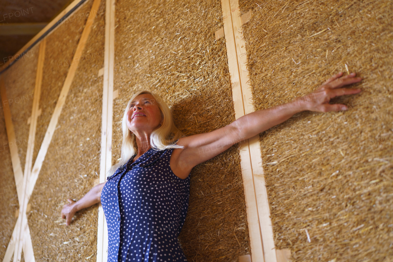 A happy senior woman inside of her new unfinished ecological wooden house.