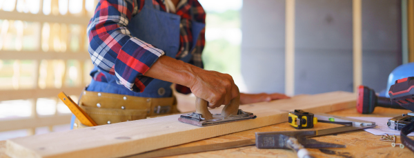 Close up of a senior woman manual working inside of her unfinished ecological wooden eco house. Concept of active independent women and seniors, eco house and healthy lifestyle.