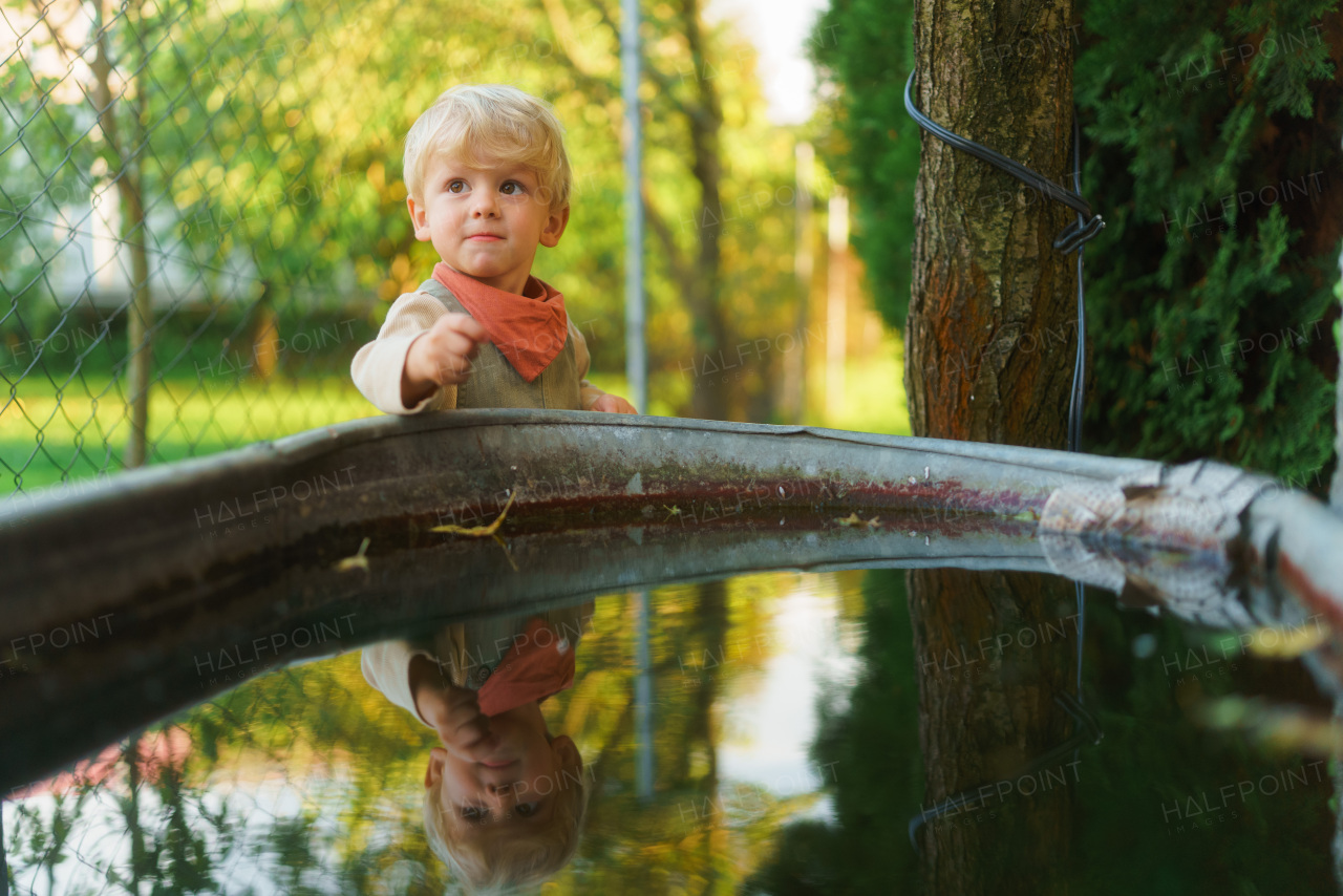 Happy little boy near water tank in the garden.