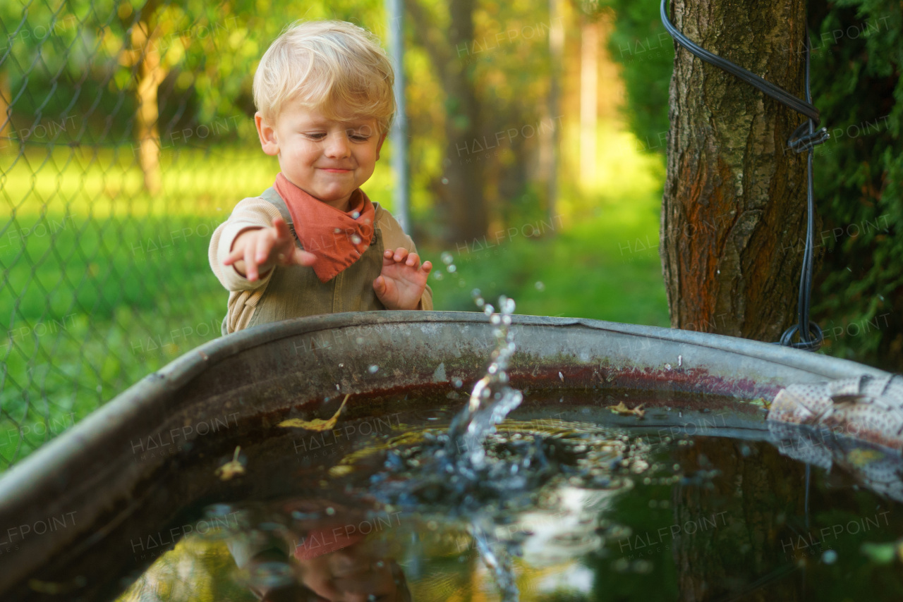 Playfull little boy throwing rocks in water in their garden.