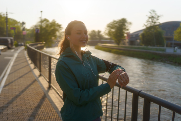 Portrait of sporty woman checking her performance on smartwach after workout session. Woman using smartwatch to sending text message, calling.