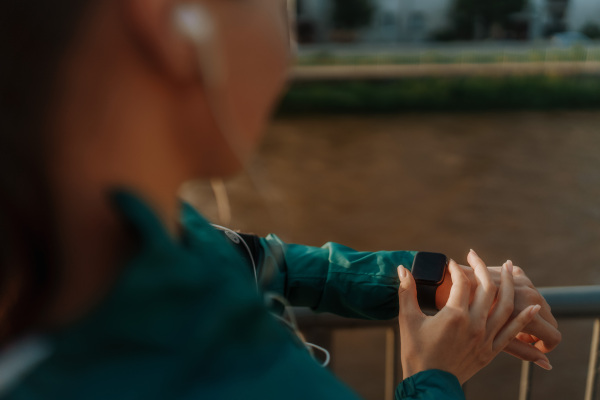 Sporty woman checking her performance on smartwach after workout session. Woman using smartwatch to sending text message, calling. Mockup for watch with black screen.