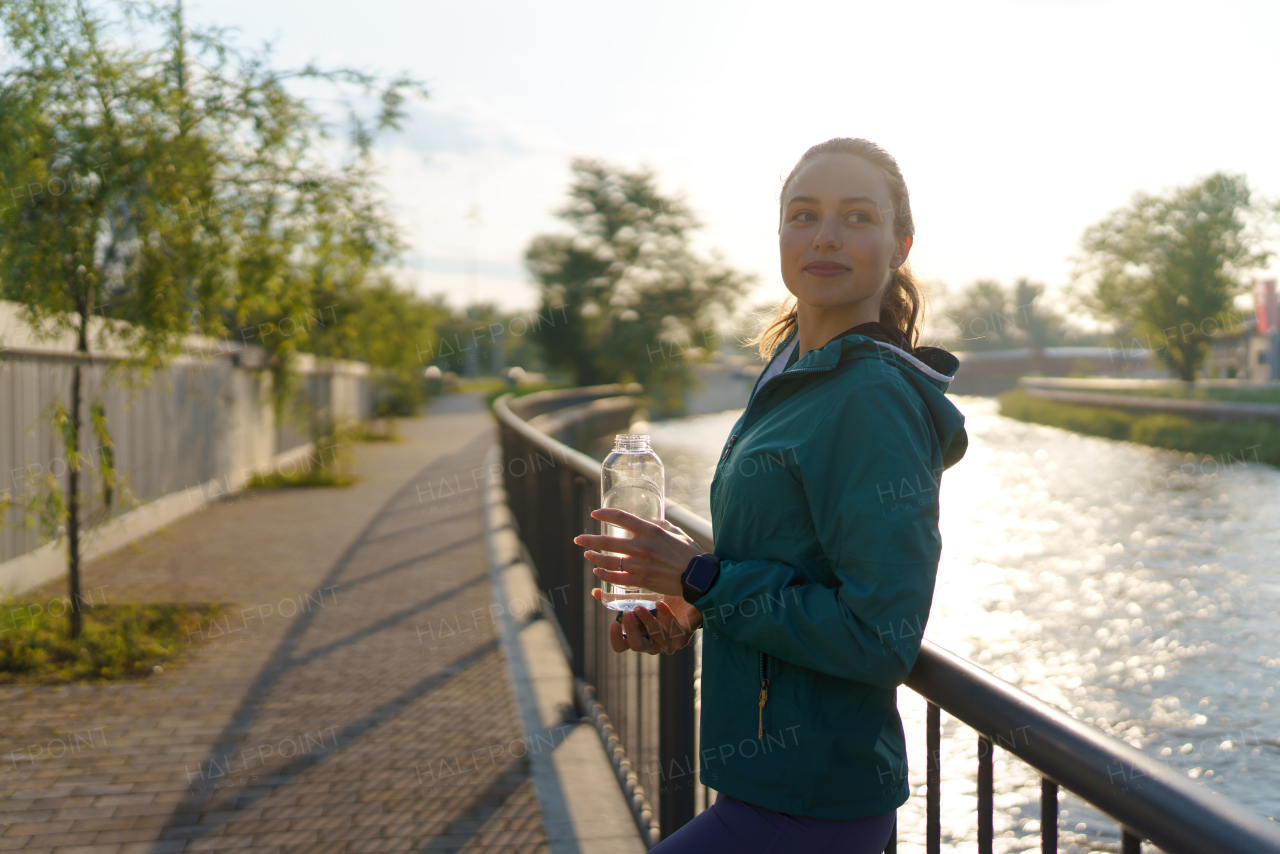 Portrait of sporty woman drinking water from bottle after workout session. Importance of hydration during workout.