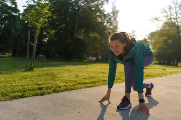 Full lenght portrait of beautiful fitness woman doing running drills in the city park. Workout at the park. Outdoor workout concept.