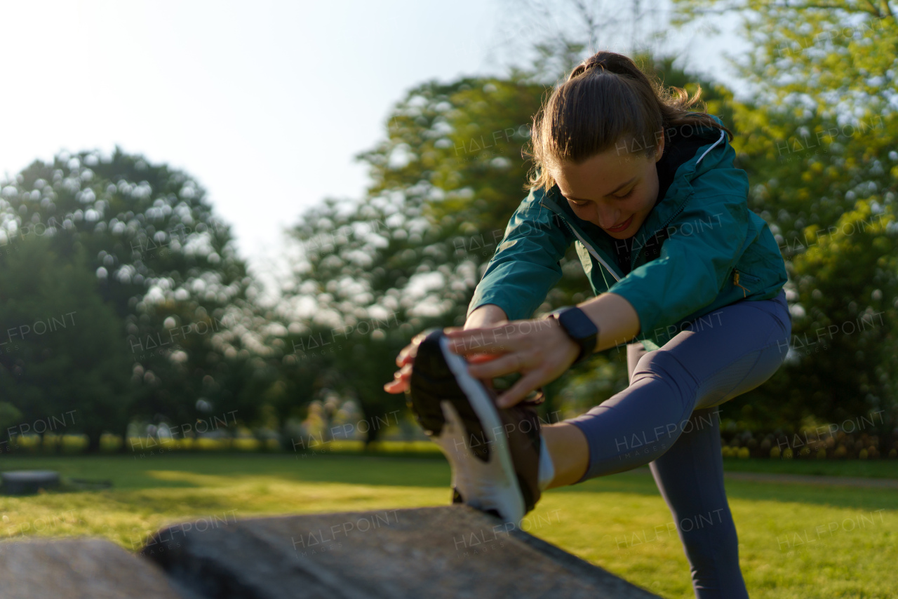 Portrait of young fitness woman stretching before outdoor workout in the city park. Healthy lifestyle concept. Copy space.